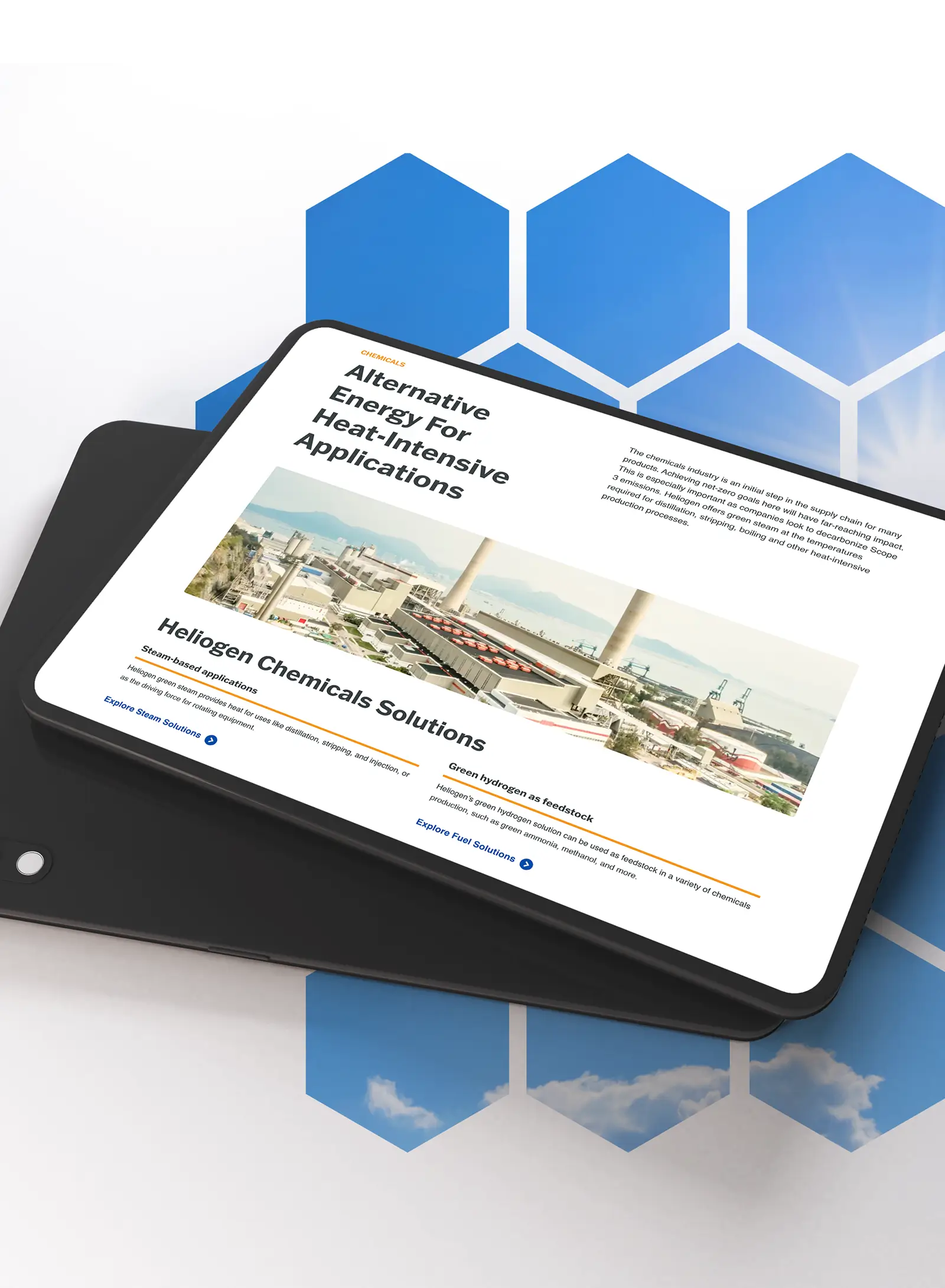 Tablet displaying Heliogen chemicals webpage about alternative energy for heat‑intensive applications, resting on another device over a blue hexagon background.