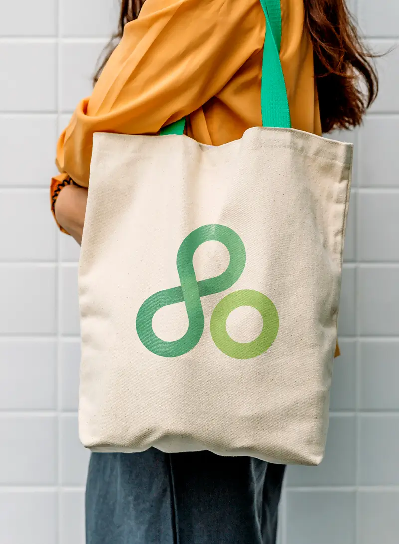 Tote bag with large green Appvance logo, carried by person in orange shirt with green handle straps