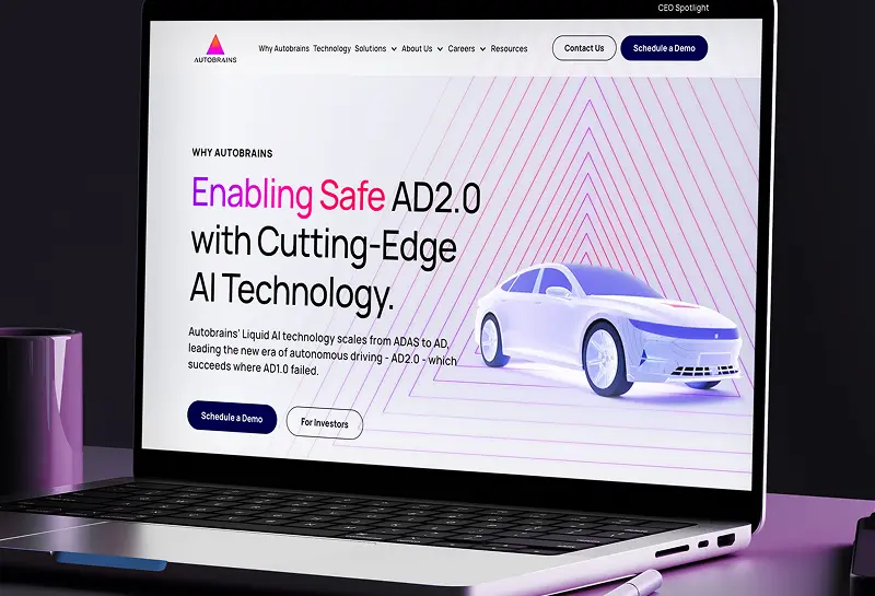 Open laptop displaying the Autobrains website hero section about safe AD2.0 autonomous driving with a white car illustration.