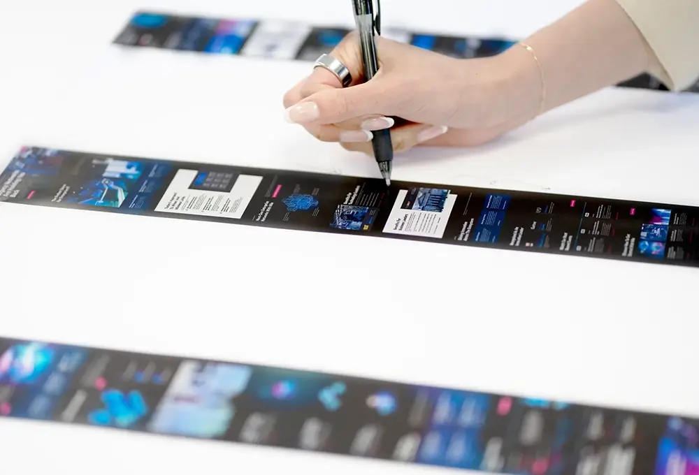 Person making edits on printed UI design strips.