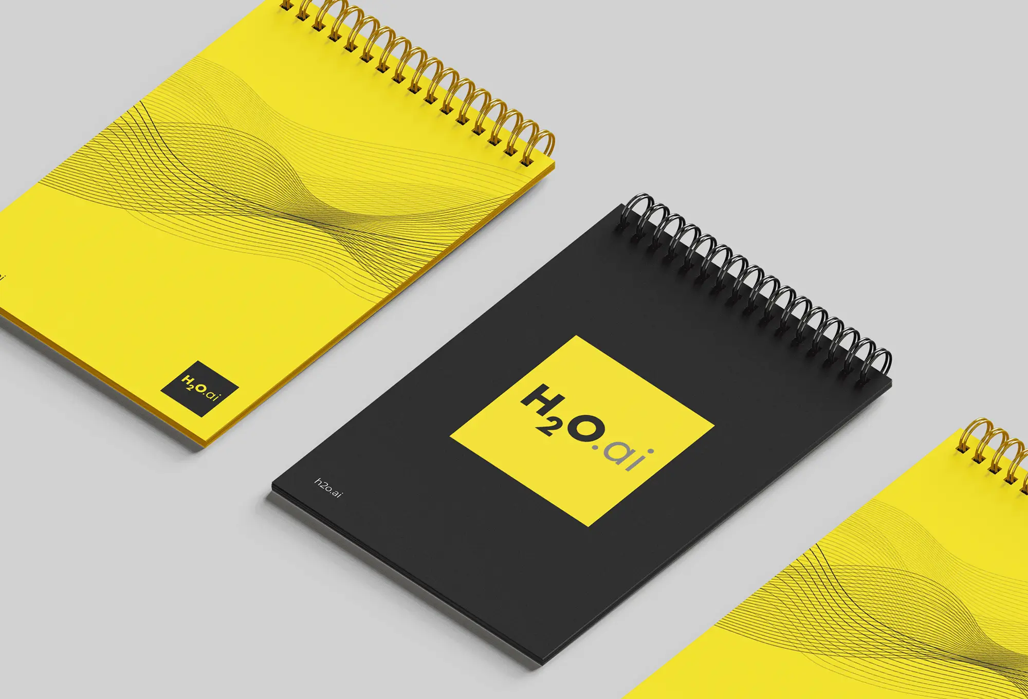 Yellow and black spiral notebooks with H2O.ai logo and abstract wave pattern on light gray background.