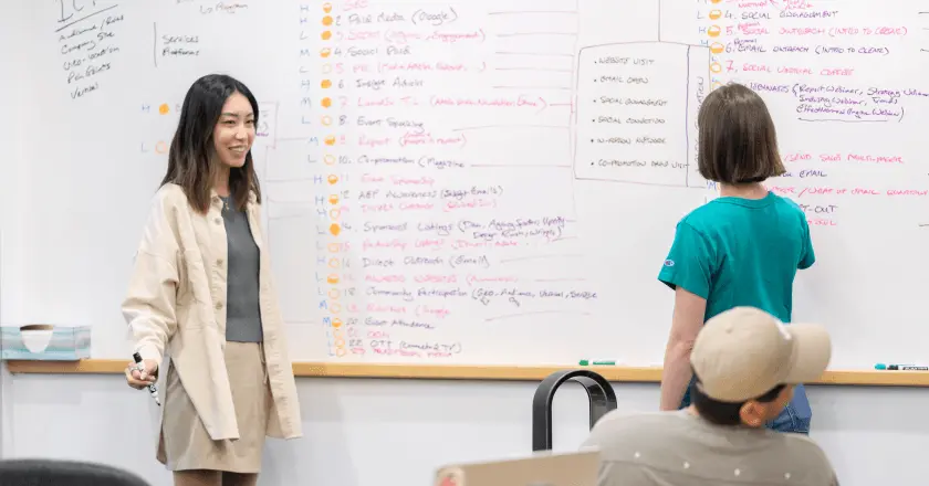Two Clear Digital team members collaborating at a whiteboard during a strategy session